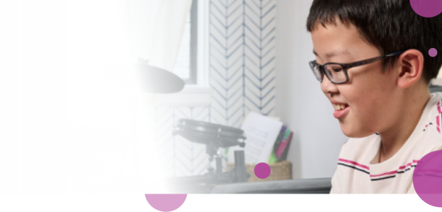 Sam, a 10-year-old who takes Koselugo for  NF1 PN, sitting on a couch and smiling